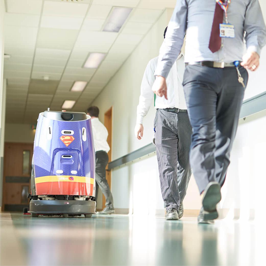 Mitie cleaning robot with a Superman design in a hospital corridor